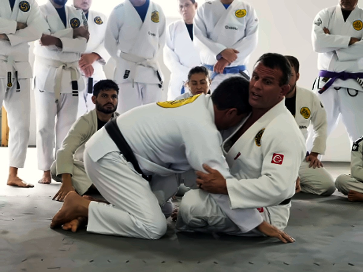 Professor demonstrando uma técnica para alunos em pé ao redor