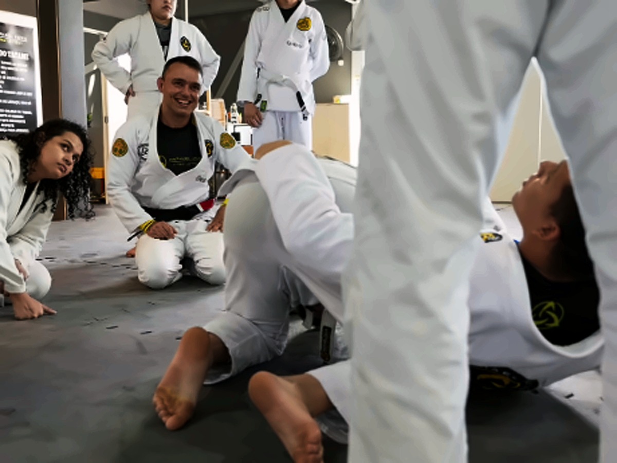 Aluno sorrindo, ajoelhado no tatame