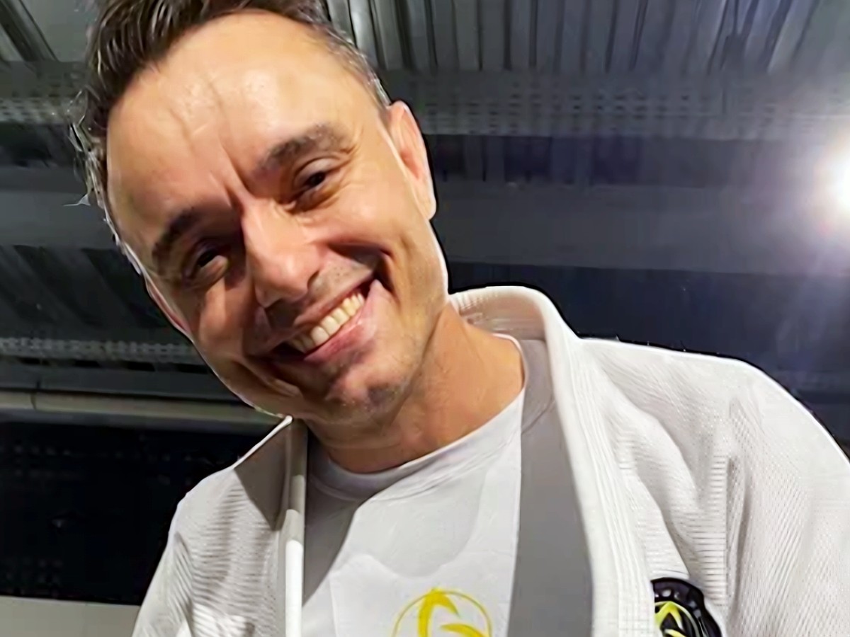 Professor Raphael Paiva sorrindo, de kimono, no dojô